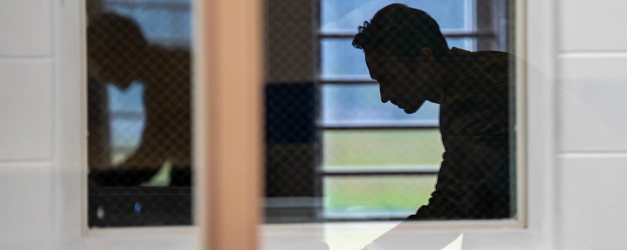 A GVSU faculty member leans over a desk to take notes